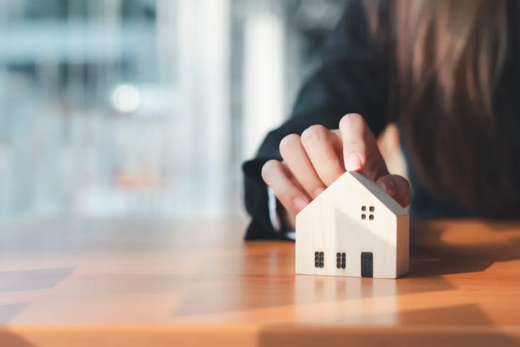 Business person with a hand on a model of a house.  Representing a Landlord looking after their property portfolio and prioritising gas safety