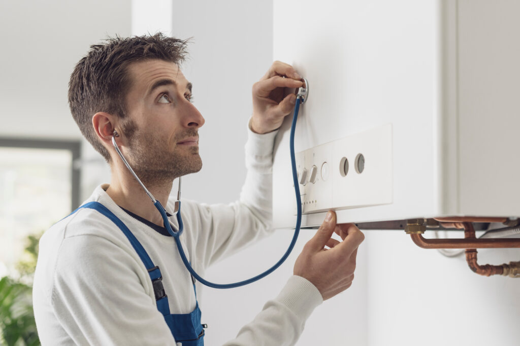 Engineer using stethoscope to diagnose boiler not working properly due to unusual sounds