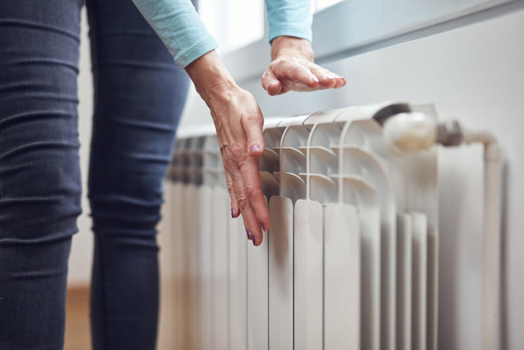 Homeowner checking cold radiator indicating boiler not working efficiently in Scottish home