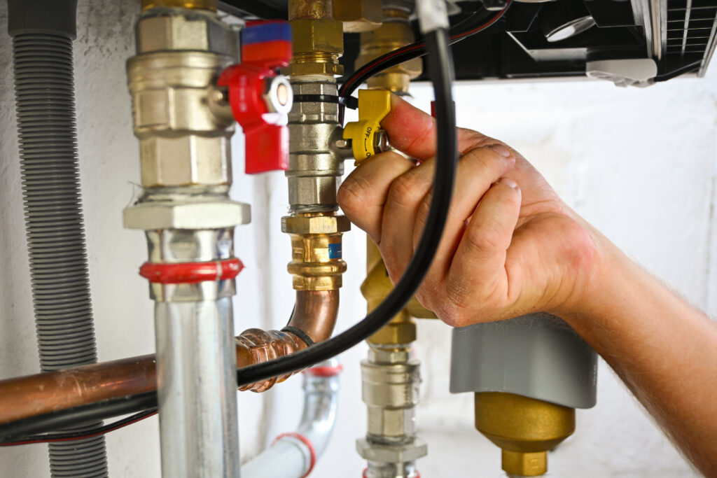 Plumber inspecting boiler valves and connections as part of boiler repair or replacement decision-making process